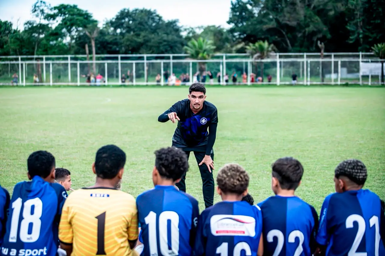 Lucas Eloy orientando jovens atletas em campo, explicando a técnica de treino